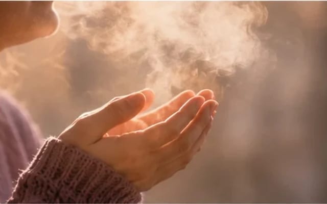 Mãos em concha com uma respiração visível na luz dourada — acalmar a ansiedade no momento