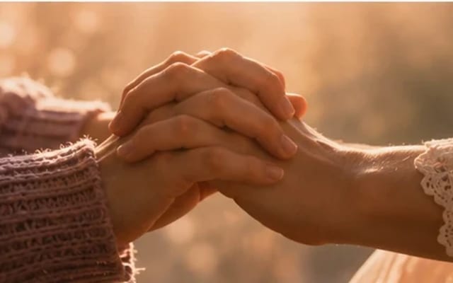 Duas mãos iguais entrelaçadas na luz suave — entrega mútua e parceria, nunca hierarquia